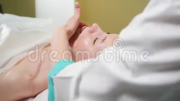美容诊所的按摩治疗医生在脸上涂抹了特殊的奶油视频的预览图