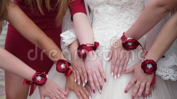 新娘和伴娘漂亮的手婚礼派对女孩的手上装饰着红花时尚女孩视频的预览图