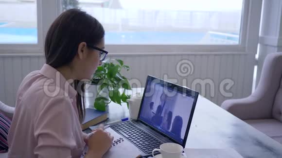 远距离学习聪明女孩眼镜通过在线视频教育自我发展使用笔记本电脑和视频的预览图