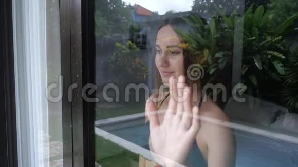 女人望着窗外挥手向某人道别4K慢动作视频的预览图