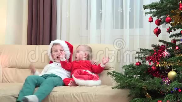 快乐的兄弟拥抱微笑笑着靠近圣诞树圣诞老人服装视频的预览图