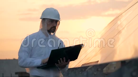 男工程师正在观察太阳能建筑并使用笔记本电脑视频的预览图