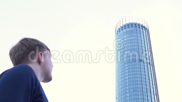 人的后视图看玻璃建筑媒体人站着看现代办公楼的玻璃立面视频的预览图