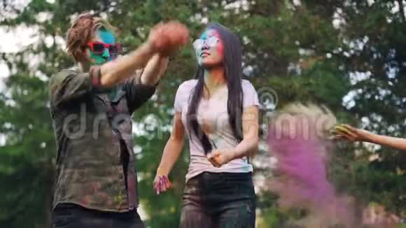 一对美丽幸福的夫妇亚洲女孩和高加索男人在霍利节跳舞投掷五颜六色的油漆视频的预览图