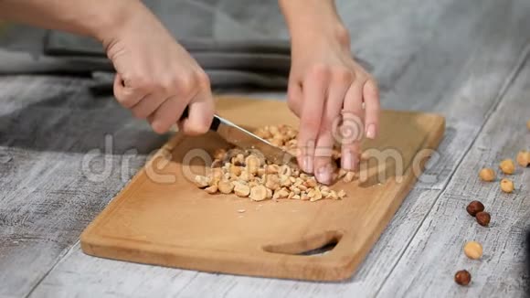女厨师手在木切割板上切榛子视频的预览图