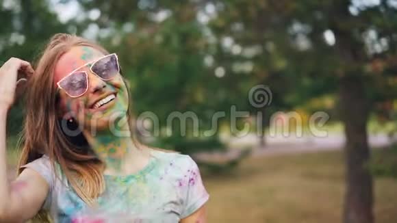 在霍利节上一位迷人的年轻女子脸上涂满了五颜六色的颜料微笑着着看着镜头抚摸着视频的预览图