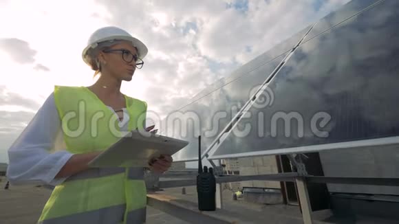 女太阳能检查员站在屋顶上正在电脑上工作视频的预览图