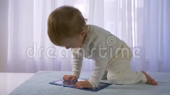 现代童年可爱的小男孩在明亮的房间里玩平板电脑视频的预览图