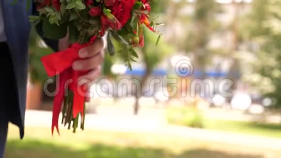 男人给女孩一束红玫瑰特写镜头新郎给他心爱的新娘送花新娘持有视频的预览图