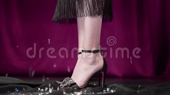 女人穿着高跟鞋在背景上穿着闪闪发光的衣服腿穿着优雅的鞋子和衣服女人视频的预览图