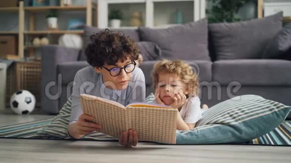 年轻女子妈妈正在给躺在毯子上的孩子读书视频的预览图