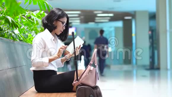 女商人坐在火车站拿着袋子视频的预览图