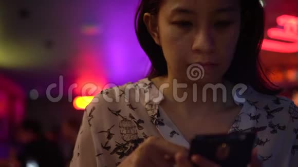 亚洲女人晚上在霓虹灯酒吧打电话视频的预览图