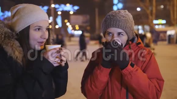 两个女孩冬天晚上在城里喝咖啡和聊天圣诞节晚上走两个朋友视频的预览图