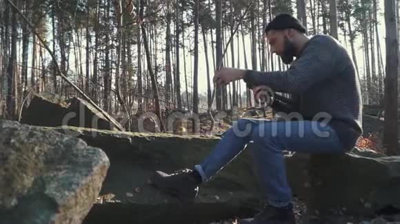 长胡子的家伙在森林里砍了一把斧头粗鲁的男人坐在户外用斧头视频的预览图