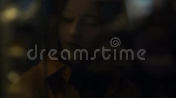 背景模糊的橱窗后面黑暗中的年轻女子视频的预览图