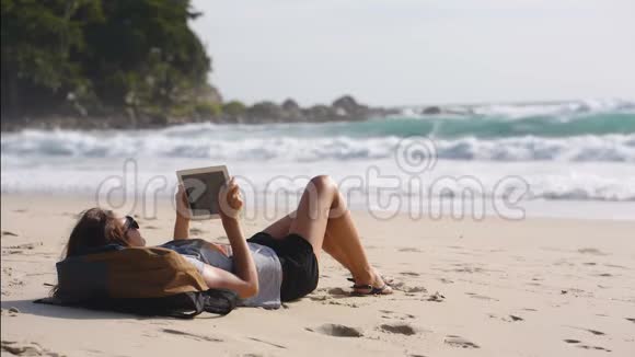 女性旅行者自由职业者在海滩上使用平板电脑视频的预览图