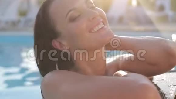 性感的女人黑发穿着优雅的泳衣在露天游泳池放松视频的预览图