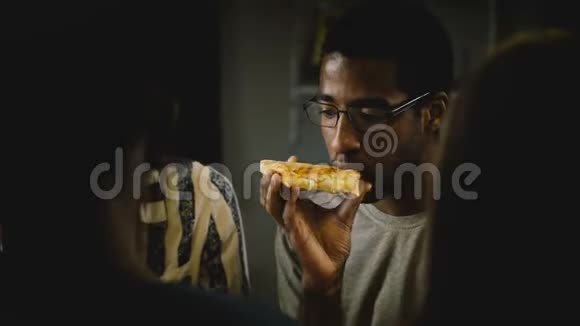 非裔美国年轻人在一个休闲的家庭聚会上吃披萨年轻人在家里的厨房里享受快餐视频的预览图