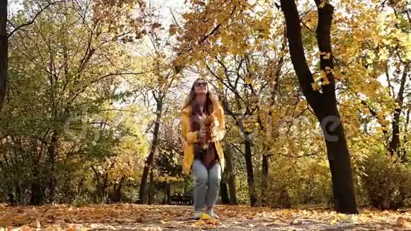 穿着黄色雨衣的金发美女在公园里扔秋叶视频的预览图