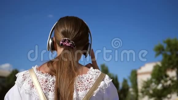 穿着白色连衣裙留着长发的少女在城市的蓝天上穿梭慢动作一个年轻的女孩视频的预览图