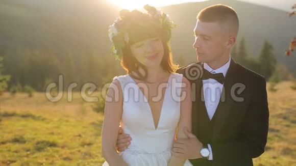 日落时分可爱的新婚夫妇新郎亲吻新娘慢动作视频的预览图
