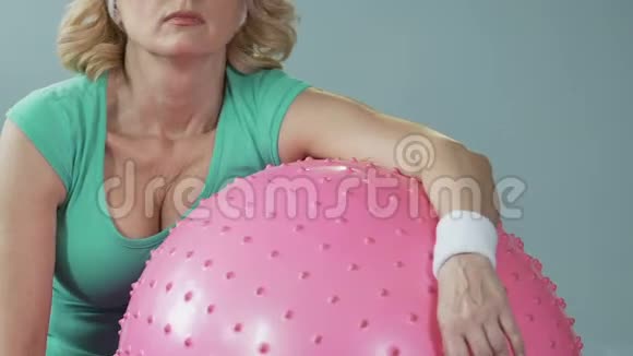 运动后躺在健身球上的困乏中年妇女视频的预览图