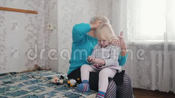 祖母用梳子梳她的孙女金发视频的预览图