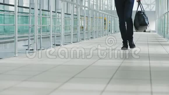 一个带手提包的年轻人走在现代化的机场候机楼里视频的预览图