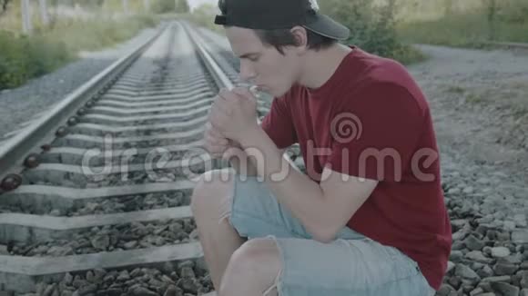年轻体贴的男孩坐在栏杆上抽烟4K视频的预览图