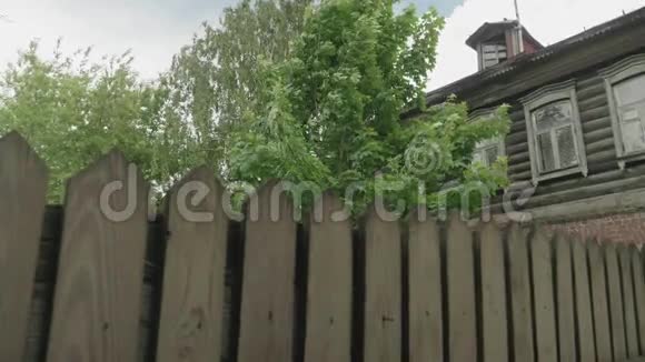 俄罗斯旧的有栅栏的木制房子旁边是绿树视频的预览图