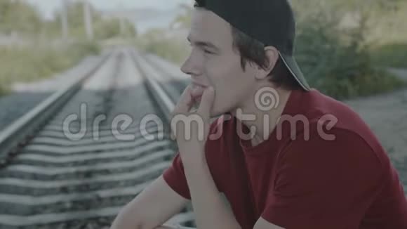 年轻体贴的男孩坐在栏杆上抽烟4K视频的预览图