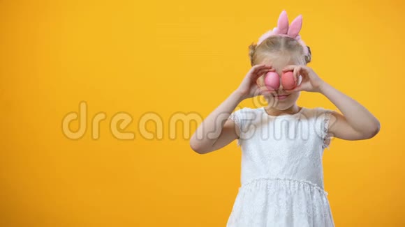 快乐的小女孩拿着彩色的复活节彩蛋和微笑的相机视频的预览图