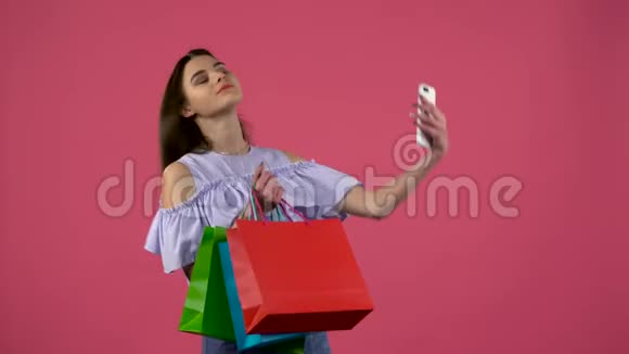 女孩用五颜六色的包裹做自拍粉色背景视频的预览图