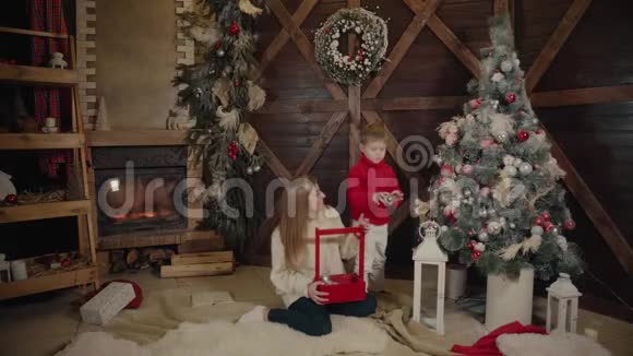 圣诞快乐新年快乐妈妈和儿子在室内装饰圣诞树充满爱的家庭视频的预览图