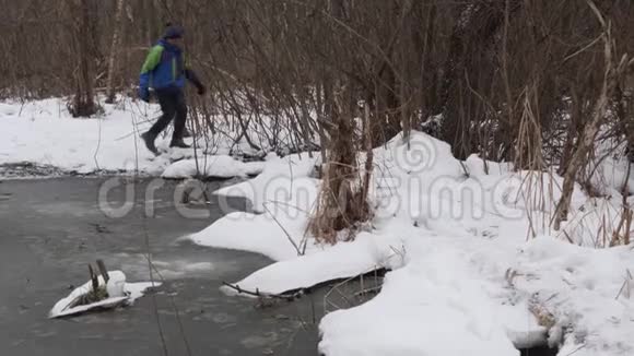 一个少年在冬天沿着一个冰冻的池塘散步视频的预览图