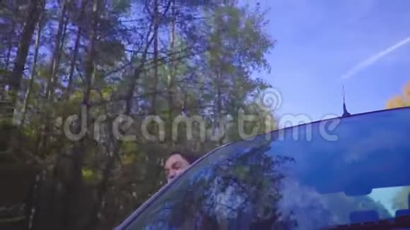 年轻的黑发开朗的女人斜倚在车窗外高兴地大叫视频的预览图