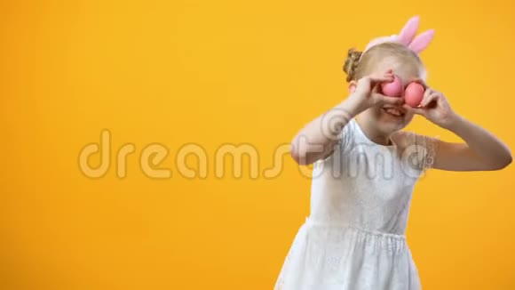 兴奋的小女孩玩彩色复活节彩蛋黄色背景童年视频的预览图