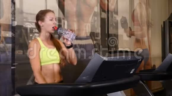 在健身房的步行道上做有氧运动运动的年轻女人在锻炼饮用水4k视频的预览图