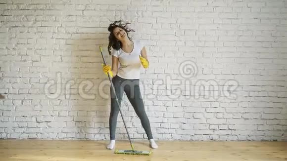 快乐的女人打扫家在拖把上唱歌就像在麦克风上唱歌玩得开心复制空间家务家务观念视频的预览图