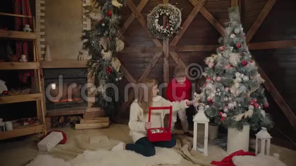 圣诞快乐新年快乐妈妈和儿子在室内装饰圣诞树充满爱的家庭视频的预览图