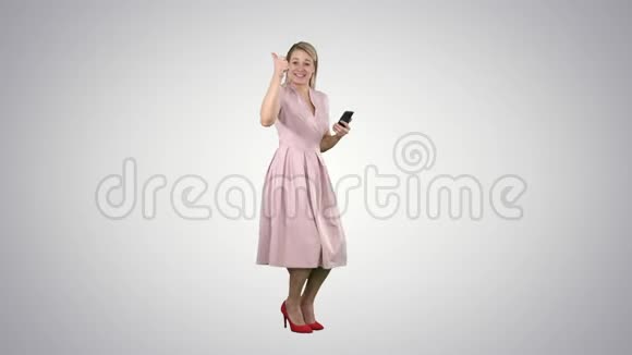笑着站在渐变背景上穿着粉红色裙子的漂亮年轻女人视频的预览图