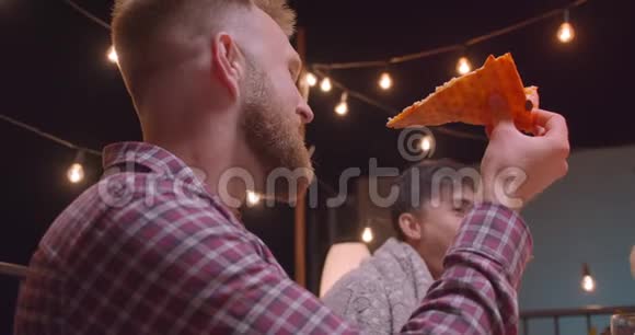 在与仙女一起度过的舒适的夜晚在清凉的聚会上在不同种族的朋友群中人们吃披萨的特写镜头视频的预览图