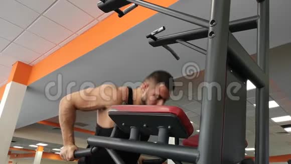 年轻肌肉男在健身房训练时在酒吧做俯卧撑视频的预览图