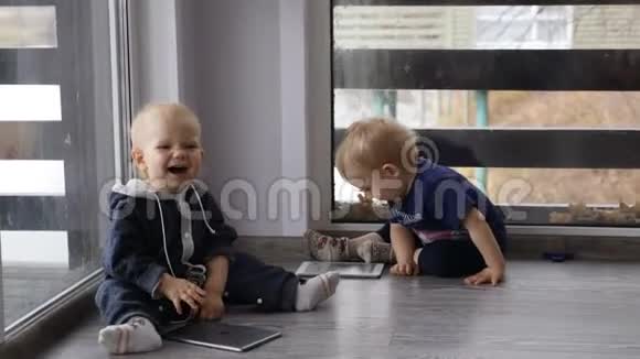 现代童年概念两个孩子坐在一起房间里的地板上放着手机和平板电脑窗户是全景视频的预览图