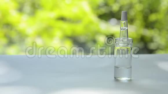 一个装有乳清的吸管的玻璃瓶放在一张白色的桌子上背景是随风摇曳的树木视频的预览图