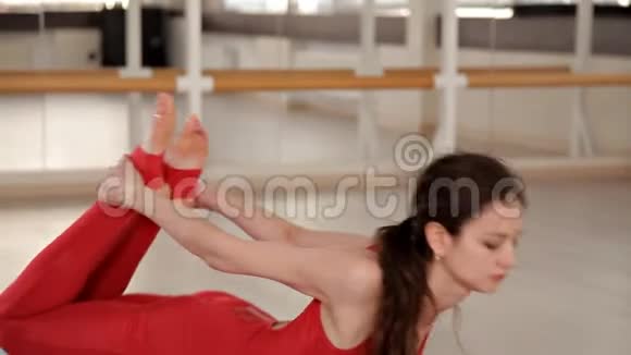 健康的年轻漂亮女孩穿着红色西装坐在大厅地板上的地毯上做运动的概念视频的预览图