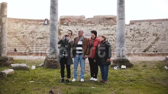 快乐的老人和妇女与年轻女孩挥手视频聊天附近的老圆形剧场废墟意大利奥斯蒂亚视频的预览图