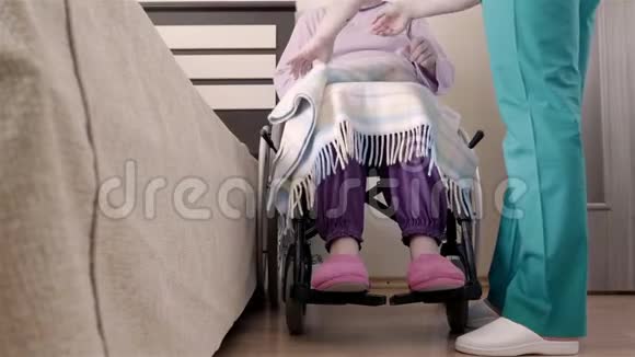 护士帮助轮椅上的老年残疾妇女卧床休息视频的预览图