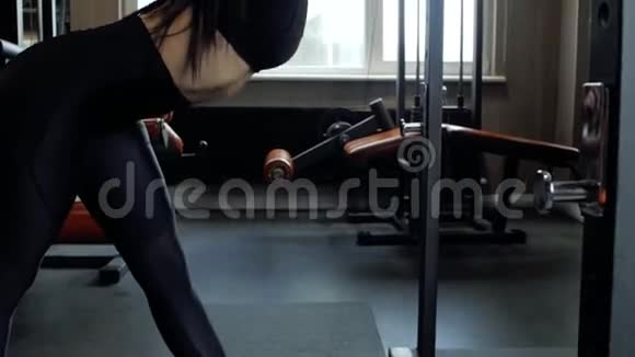 美丽的黑发女孩穿着黑色紧身裤在健身房做热身运动年轻女孩伸展身体视频的预览图